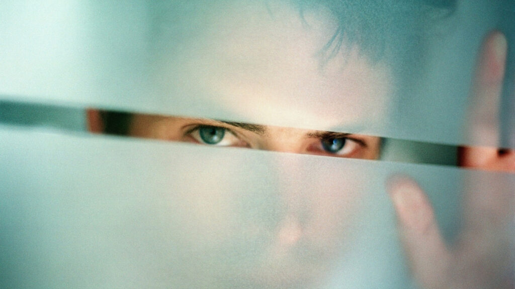 Egy férfi figyel egy ablakon keresztül