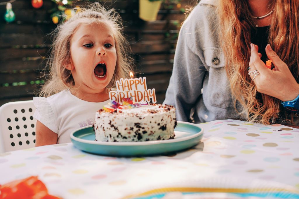 Elfújja a gyertyákat a tortáján egy kislány a születésnapján 