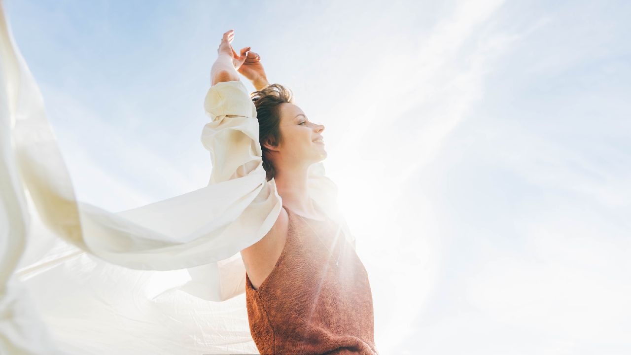 Lány mosolyog a kék ég előtt