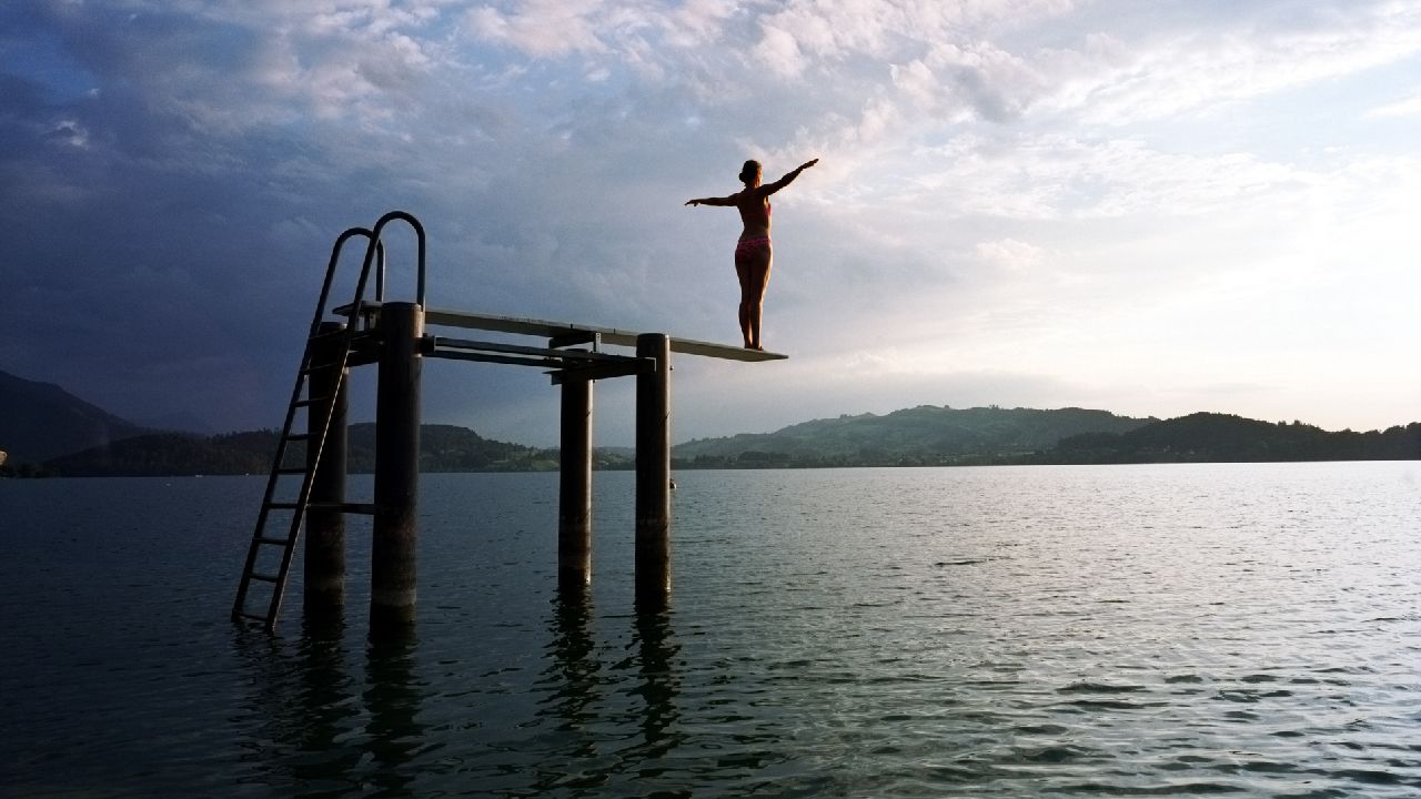 Nő áll a tó fölött ugródeszkán
