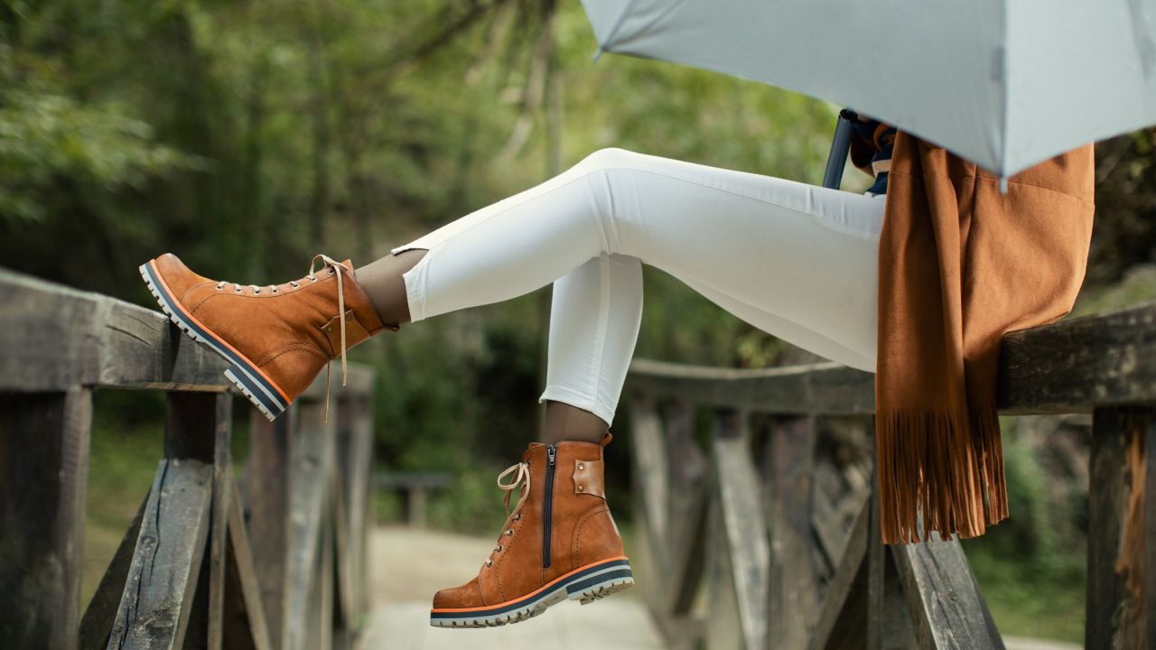 Nő ül a padon ernyővel őszi öltözékben