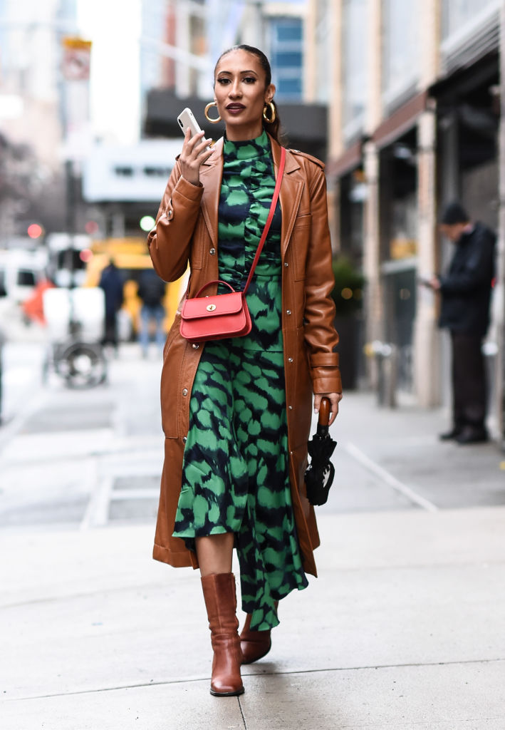 Barna kabátot mintás ruhával viselő nő az utcán