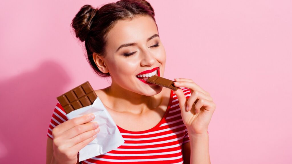 nő csíkos felsőben csokit eszik