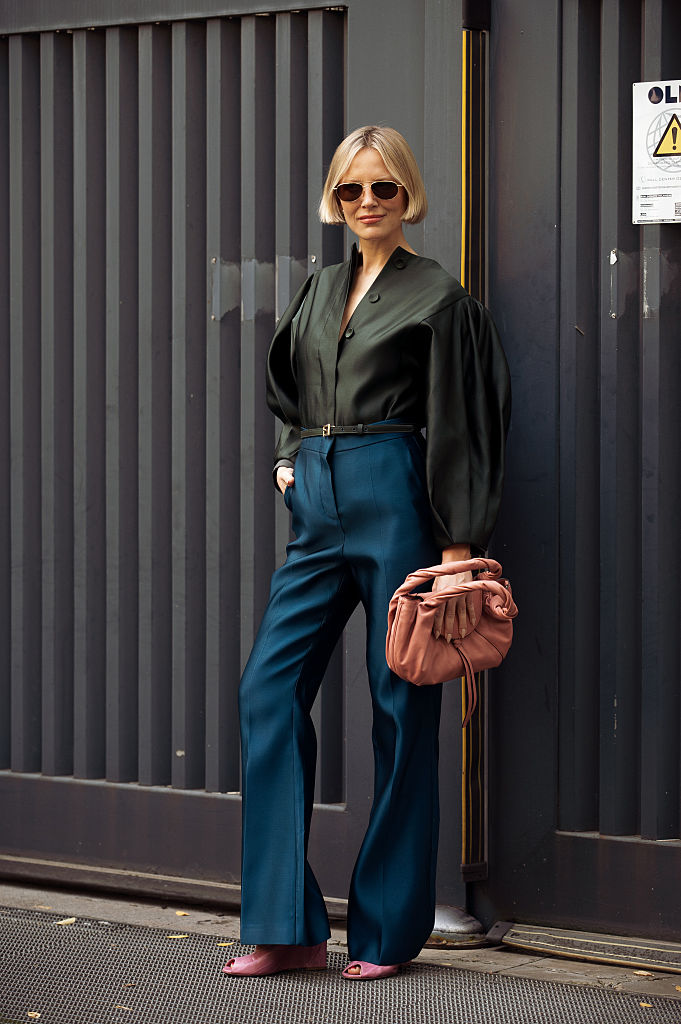 Magas derekú nadrágot és blúzt viselő nő az utcán