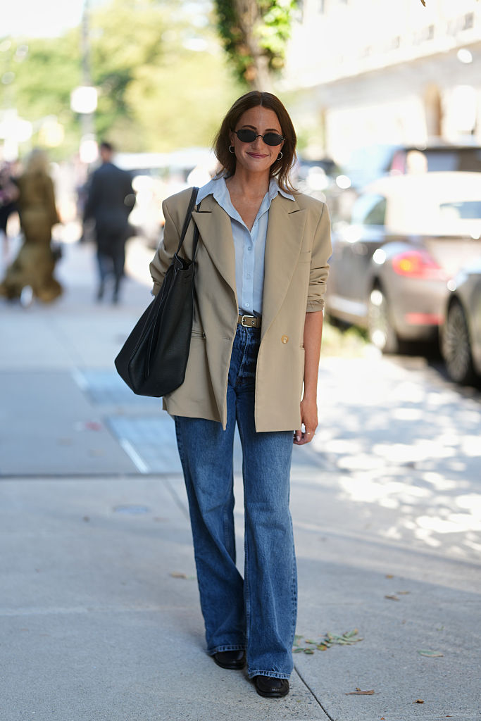 Magas derekú nadrágot, inget és blézert viselő nő az utcán