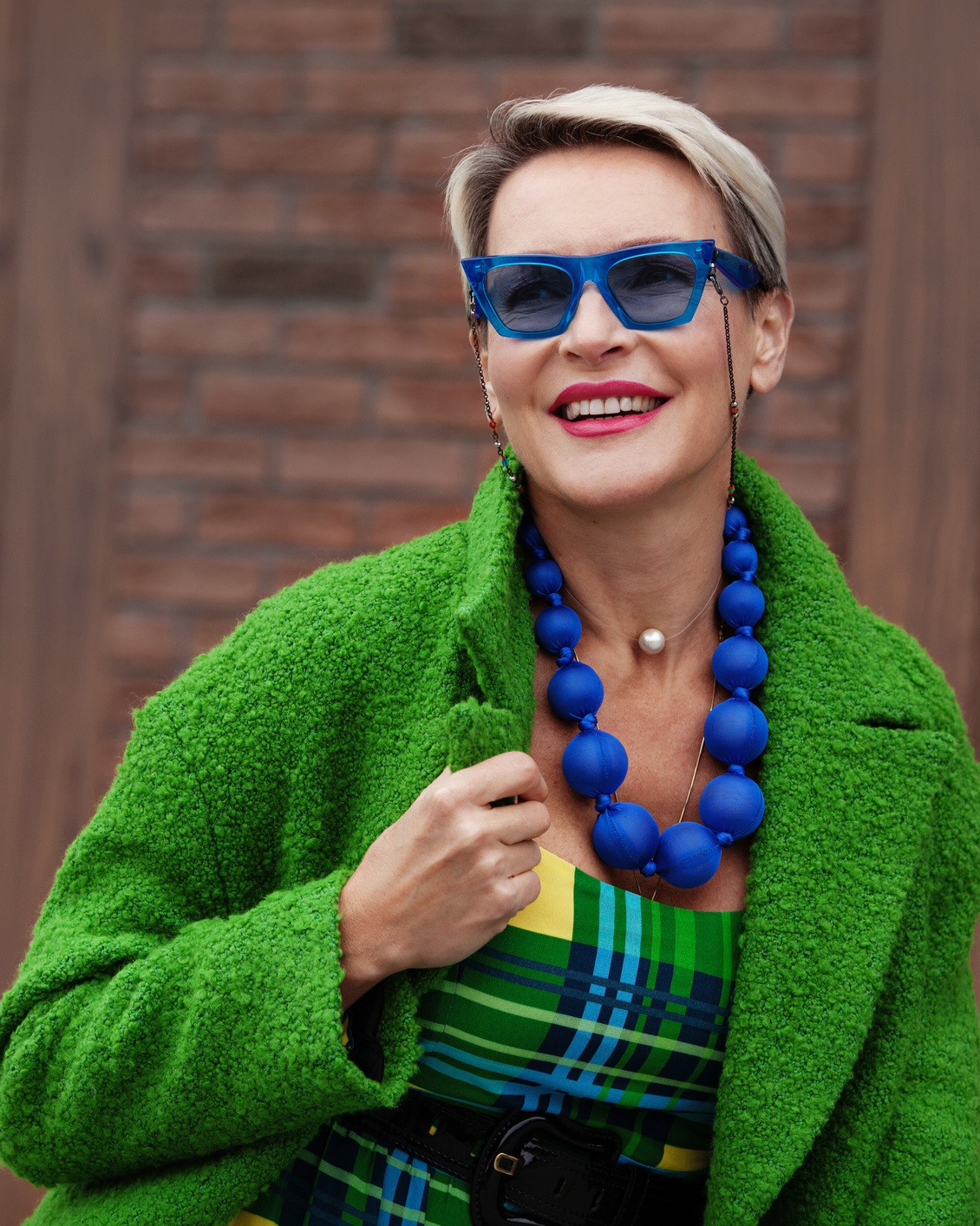 50-es nő kék napszemüvegben mosolyog.