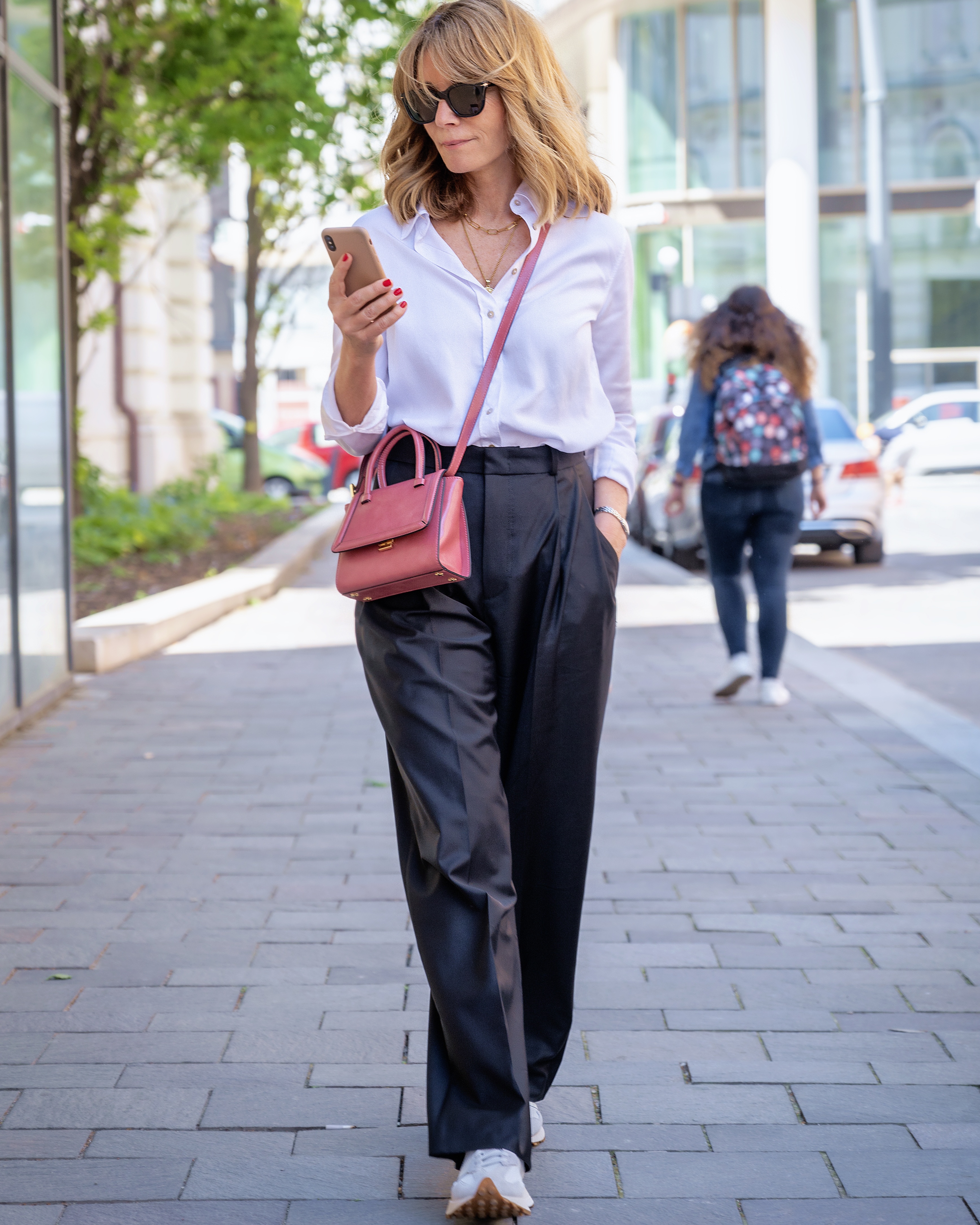 Nő fehér ingben, szövegnadrágban és sneakersben