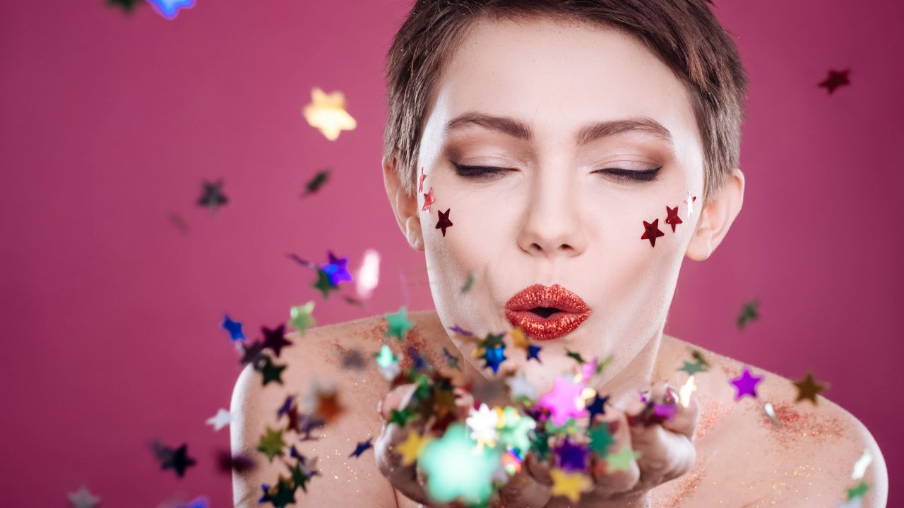 Nő belefúj a tenyerén lévő csillagkonfettibe