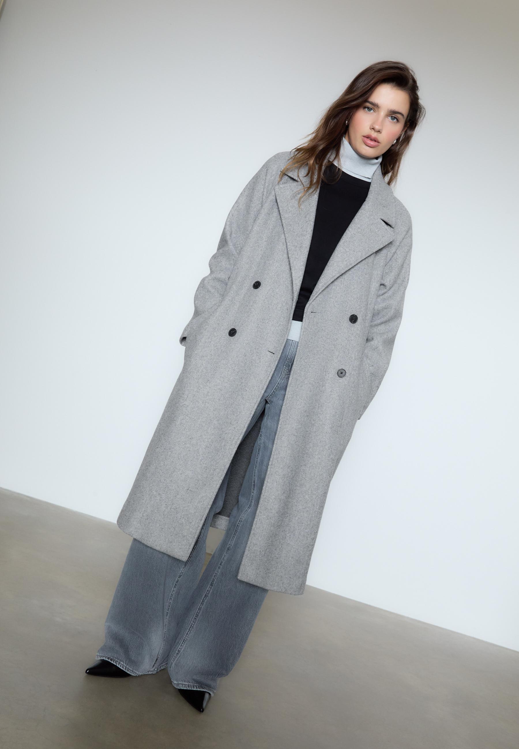 Hosszú szövetkabátot viselő modell