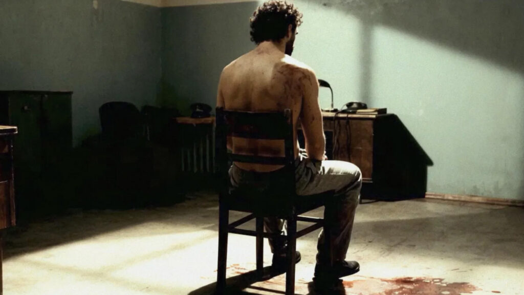 Magda Marinko háttal ül, félmeztelenül