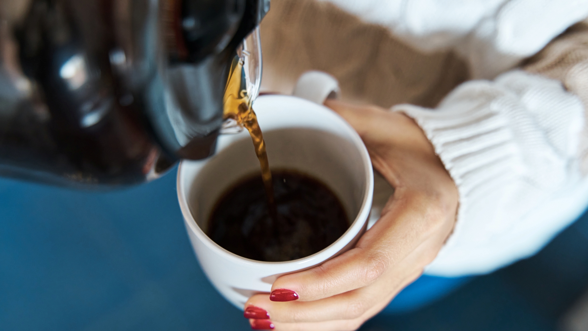 Egy nő kávét önt egy bögrébe.