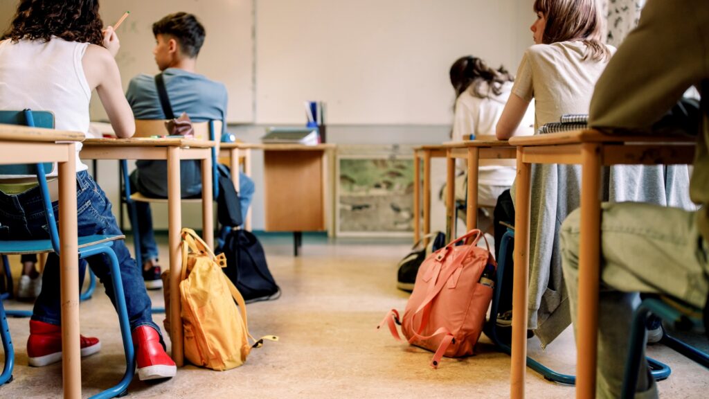 Diákok ülnek az iskolapadban.