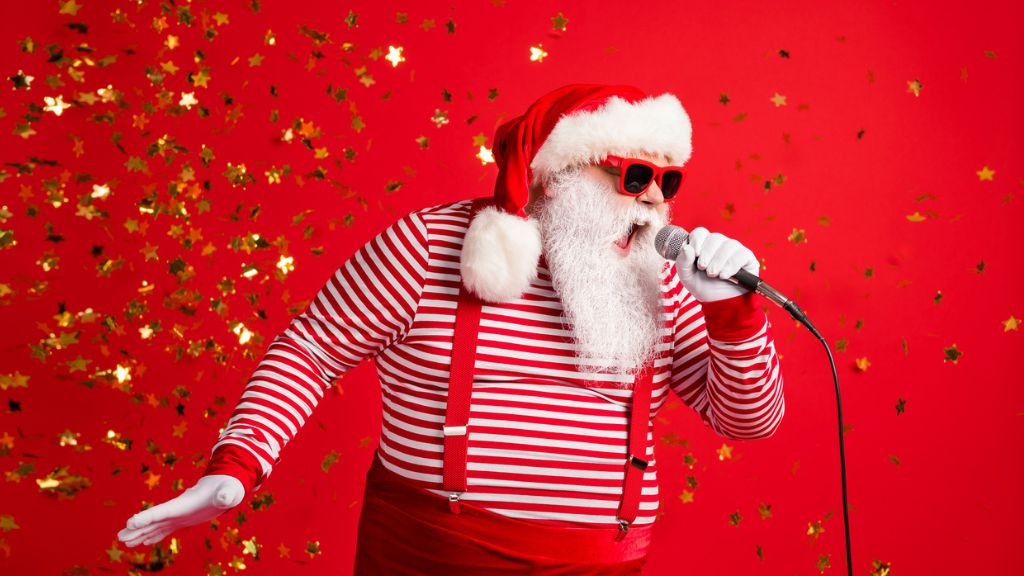 Mikulás ruhába öltözött ember énekel egy mikrofonba