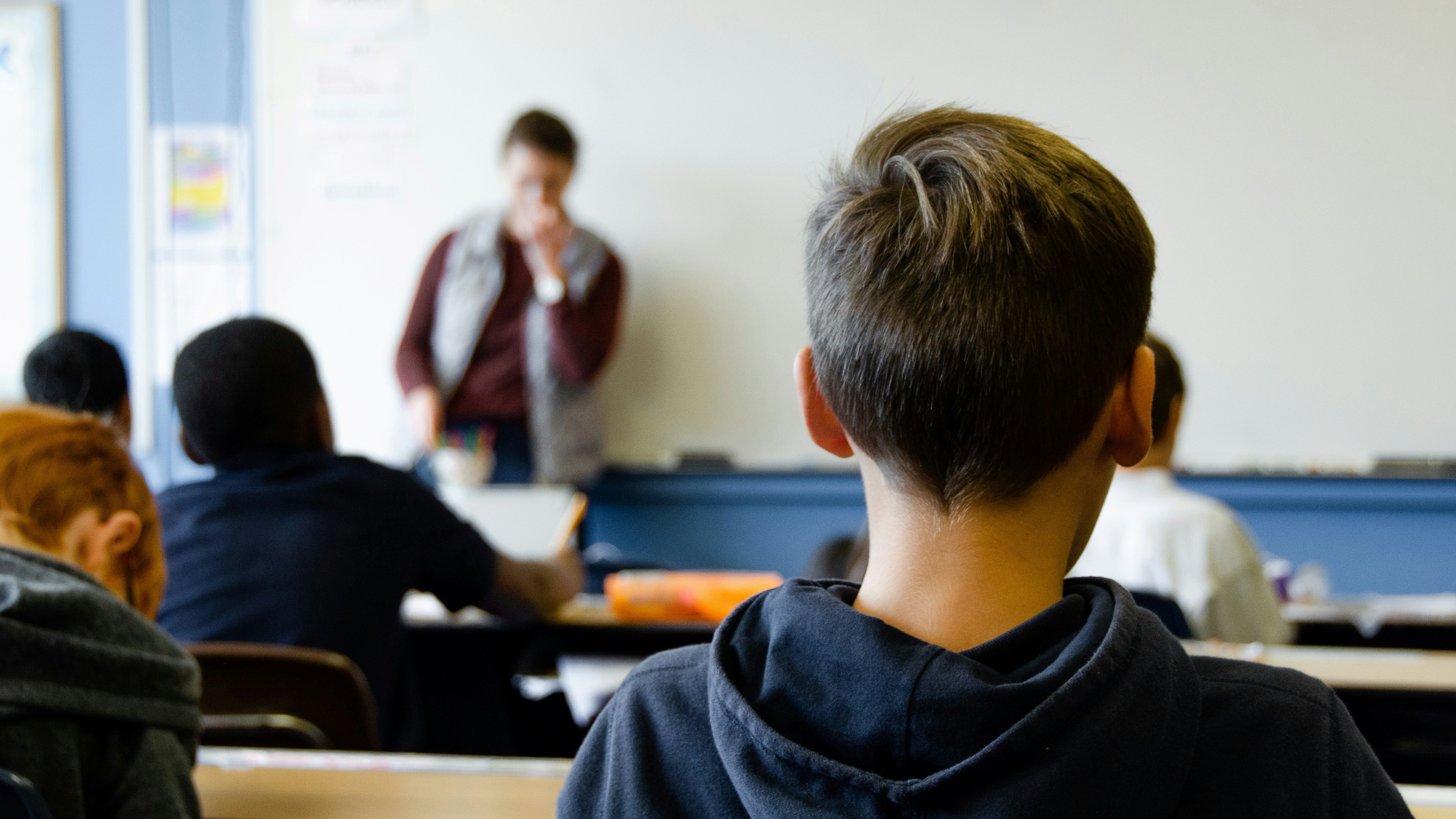 Óra egy iskolában, hátulról egy kisfiú, táblánál a tanár