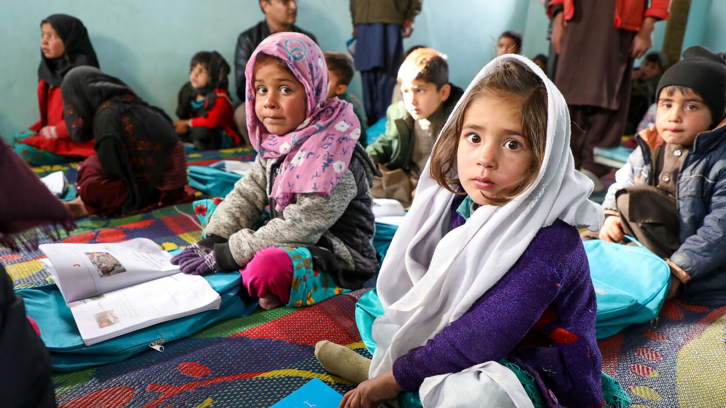 Kislányok a földön ülve tanulnak