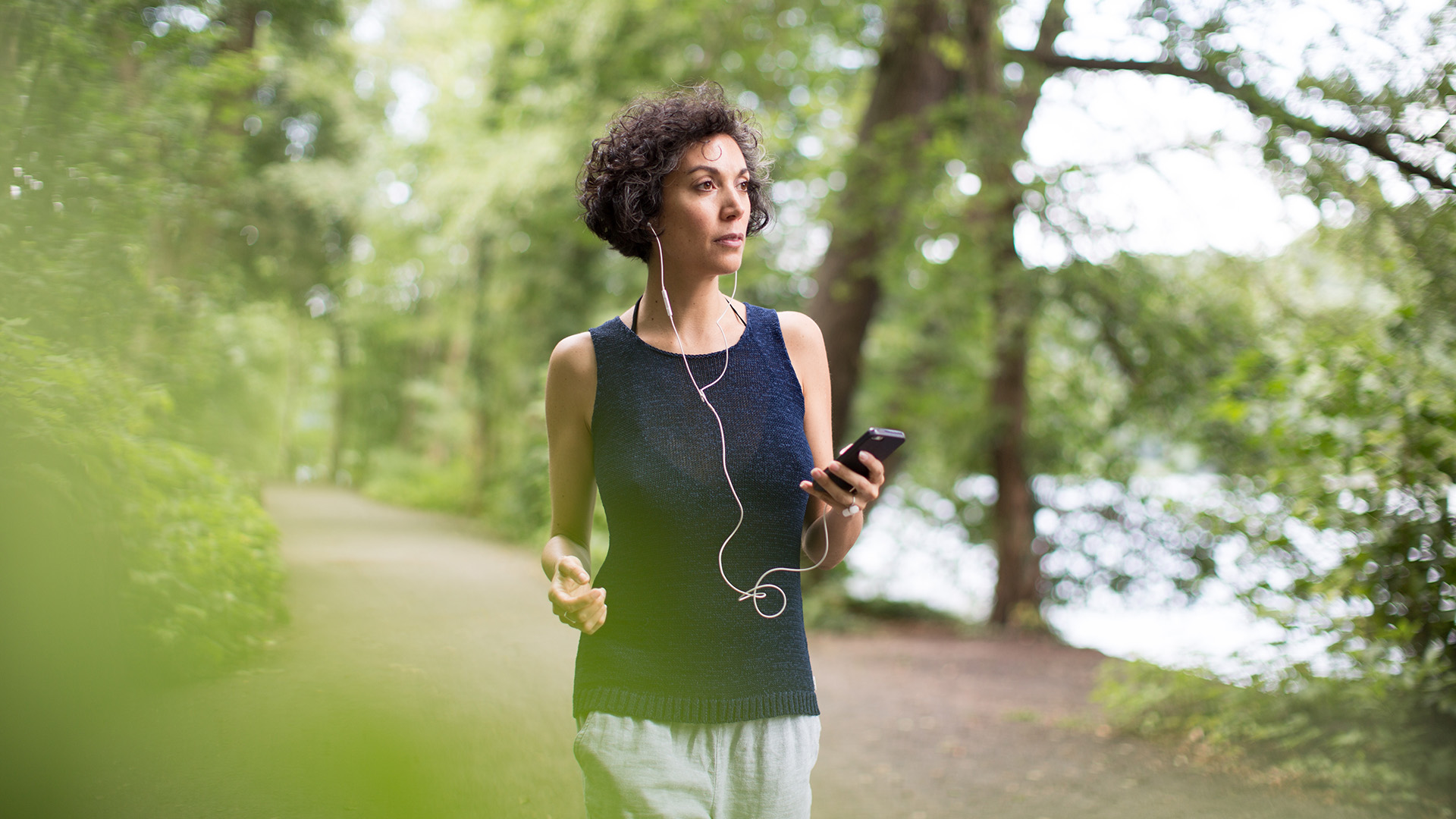 Nő sétál az erdőben telefonnal a kezében