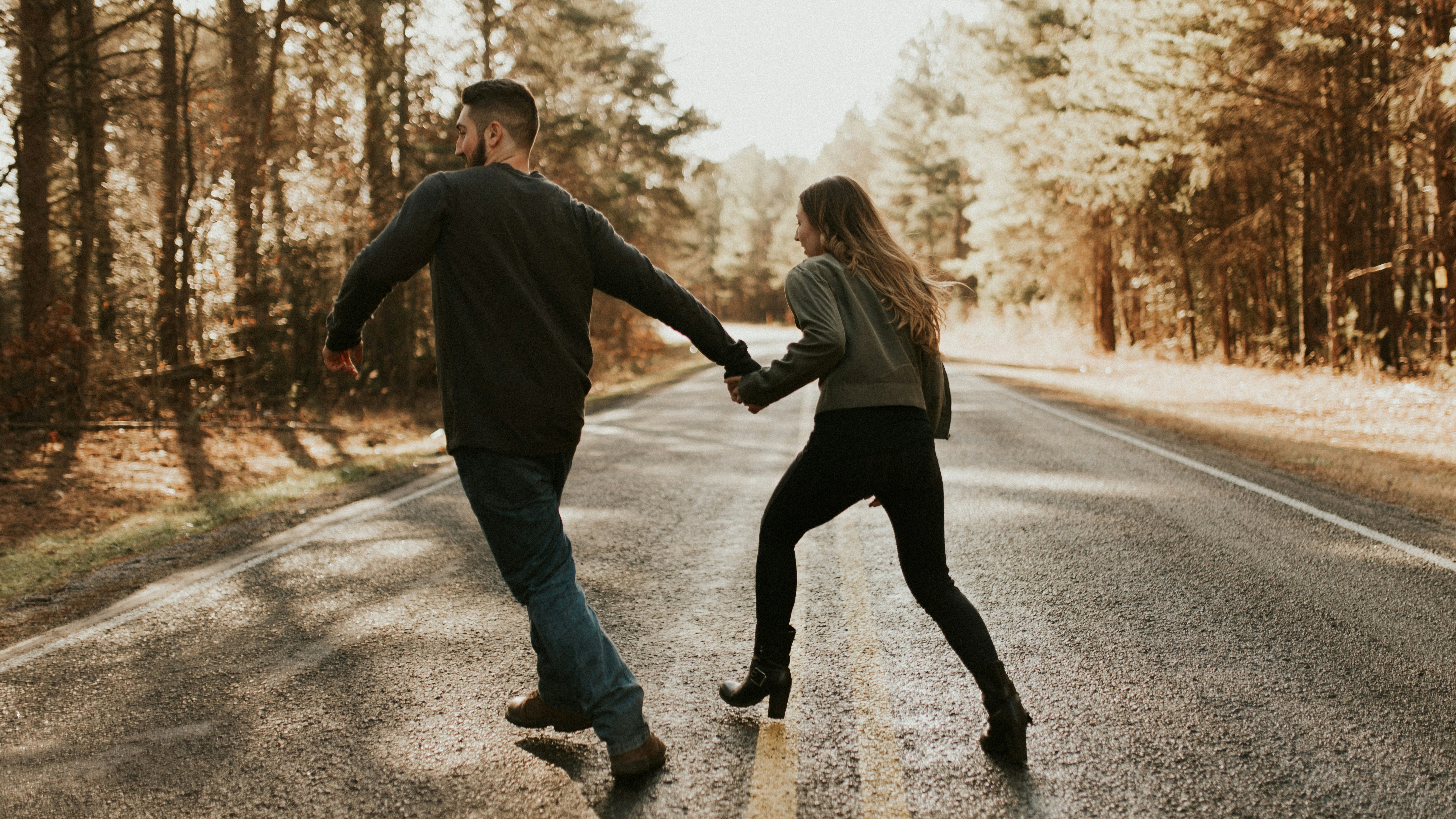 Egy fiatal pár kézenfogva fut egy úton
