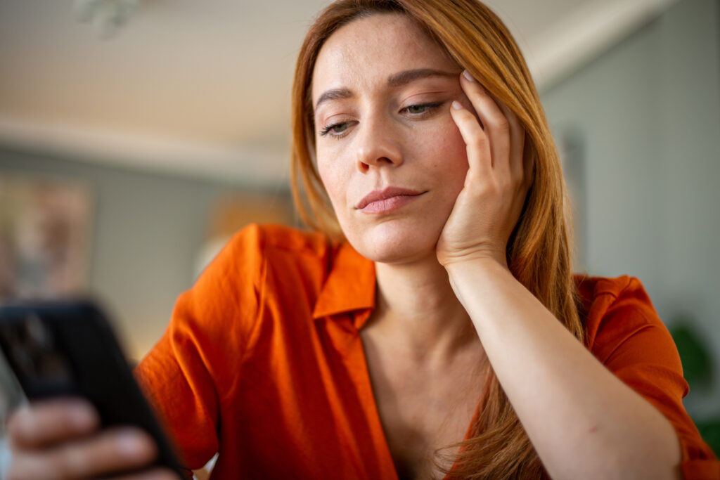 Csalódott nő telefonját böngészi