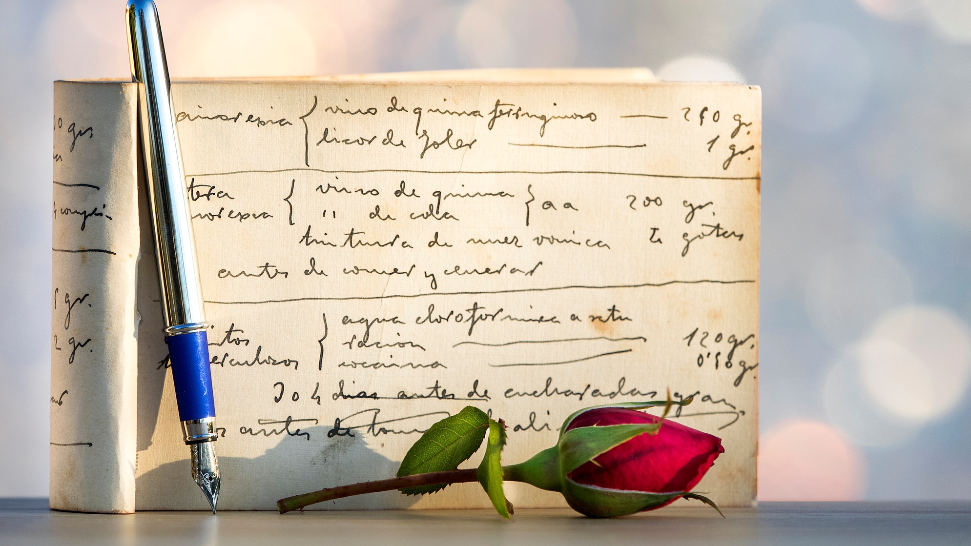 Egy papíron írás, mellette egy toll és egy rózsa
