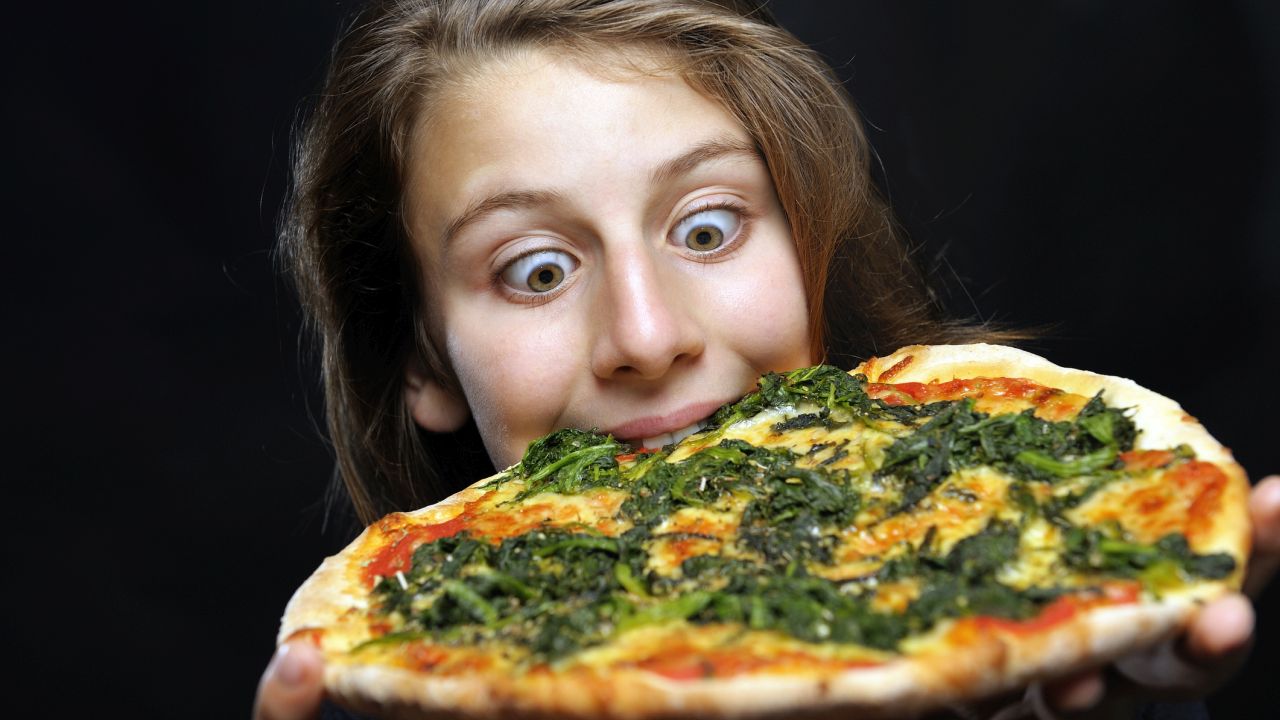 Lány spenótos pizzát eszik